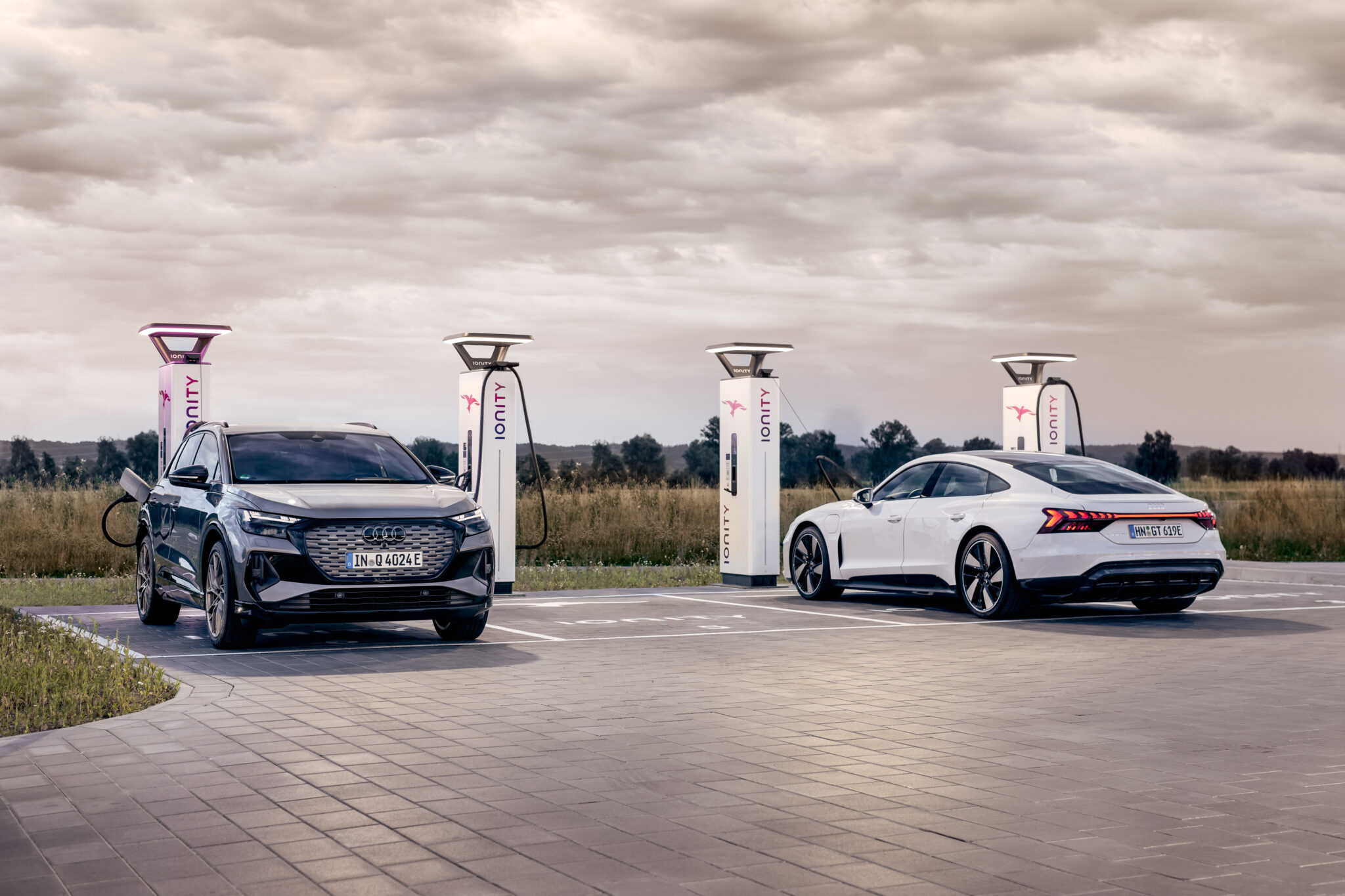 Dwa elektryczne modele Audi podczas ładowania na stacji IONITY w otwartej przestrzeni