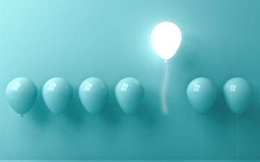 Jasny balon unoszący się ponad innymi balonami symbolizuje wyróżniającą się strategię ESG i zrównoważonego rozwoju