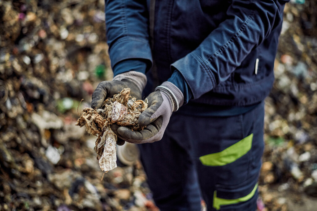 Dłonie trzymające surowiec z przetworzonych odpadów komunalnych