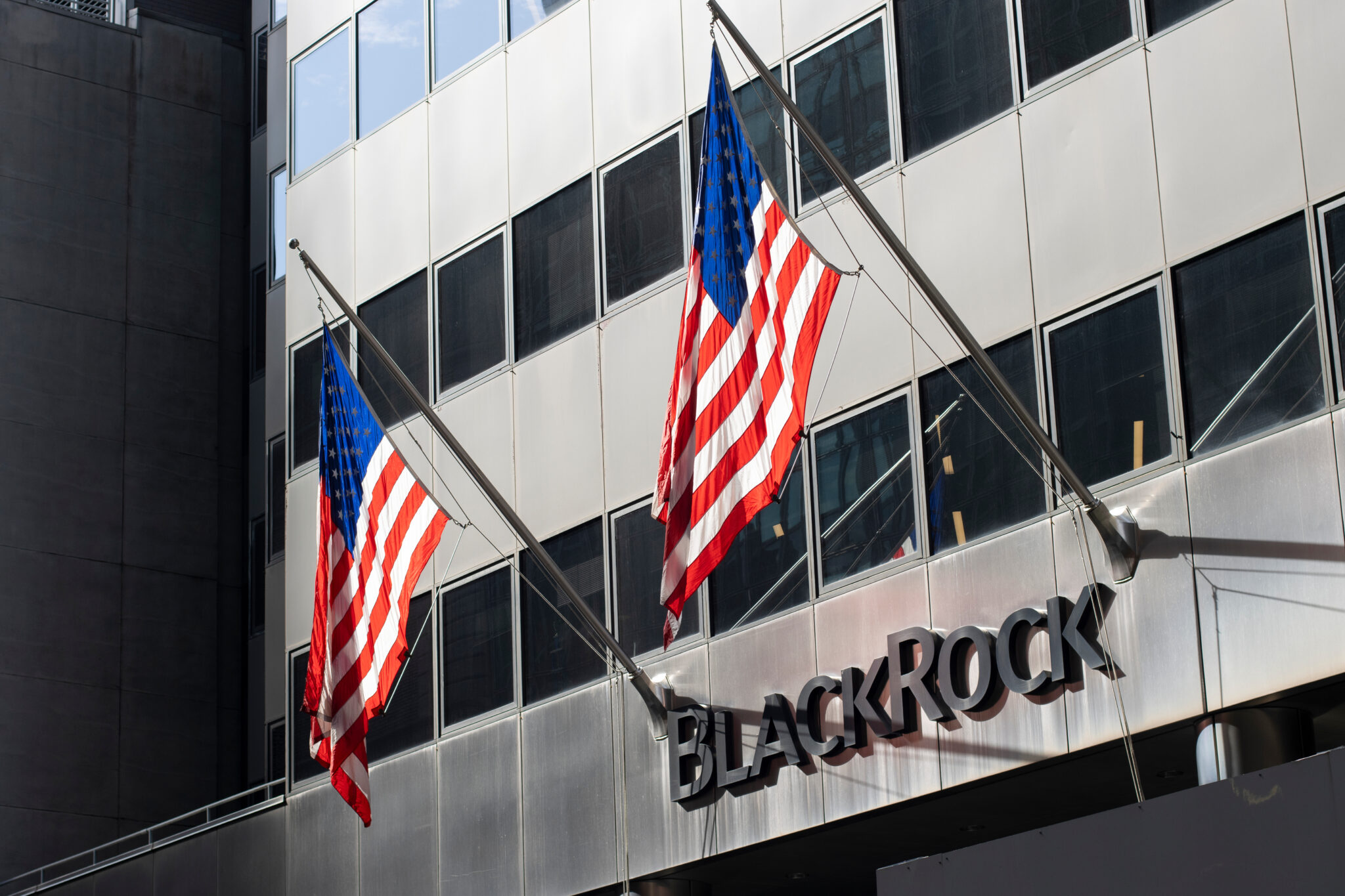 Siedziba BlackRock z amerykańskimi flagami na tle budynku biurowego