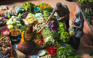 Stragan z warzywami na targu w Azji, lokalni kupcy i klienci