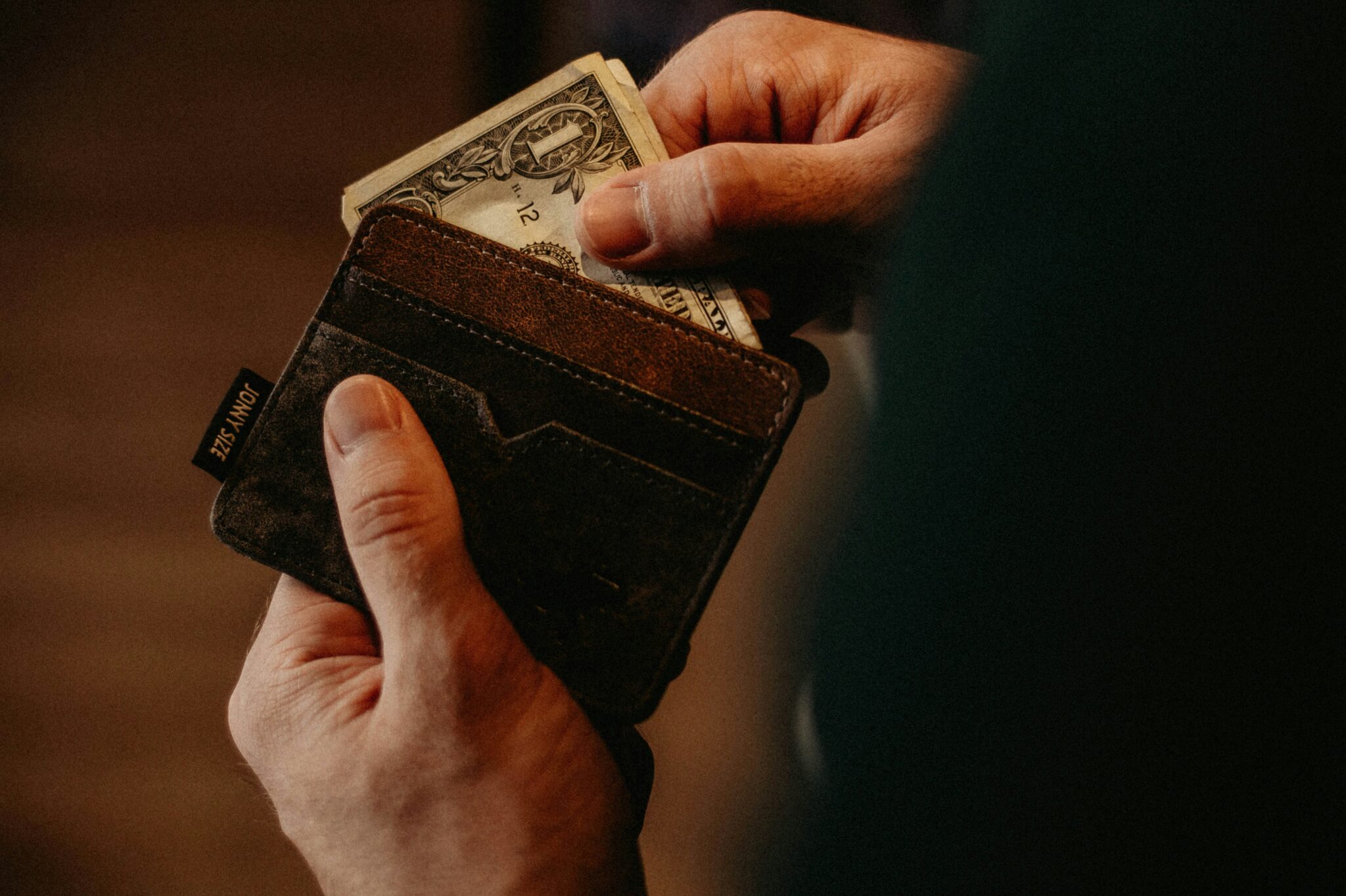Zbliżenie dłoni trzymającej portfel z dolarami