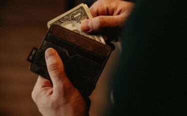 Zbliżenie dłoni trzymającej portfel z dolarami
