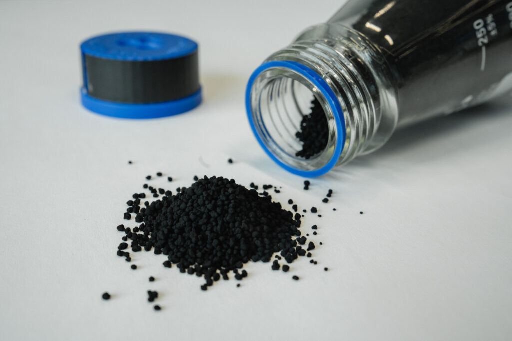 czarne granulki odzyskanej sadzy technicznej wysypane z probówki