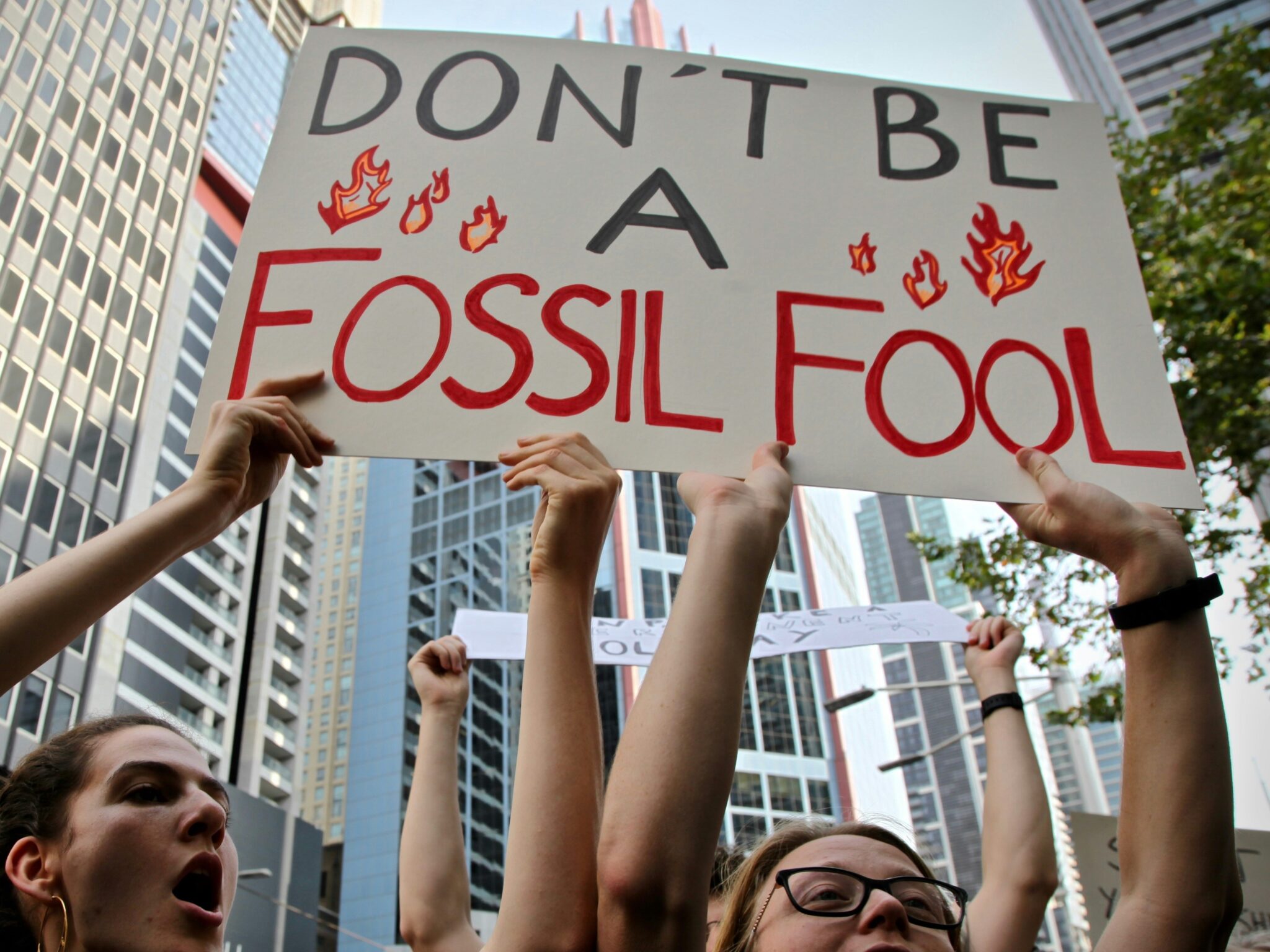 Uczestnicy protestu klimatycznego z transparentem "Don't be a fossil fool"