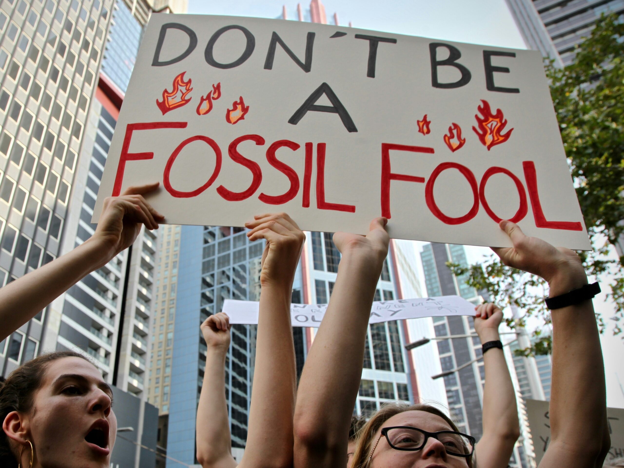 Uczestnicy protestu klimatycznego z transparentem "Don't be a fossil fool"