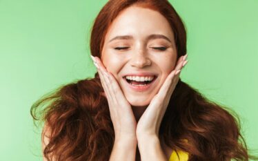 Uśmiechnięta kobieta z zadbaną cerą na zielonym tle