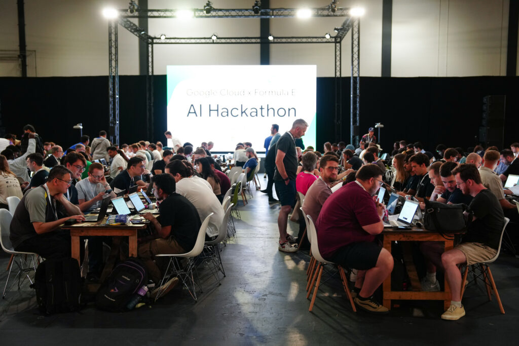 Uczestnicy Hackathonu AI Google Cloud i Formula E pracujący przy laptopach