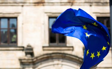 Flaga Unii Europejskiej powiewająca przed budynkiem rządowym