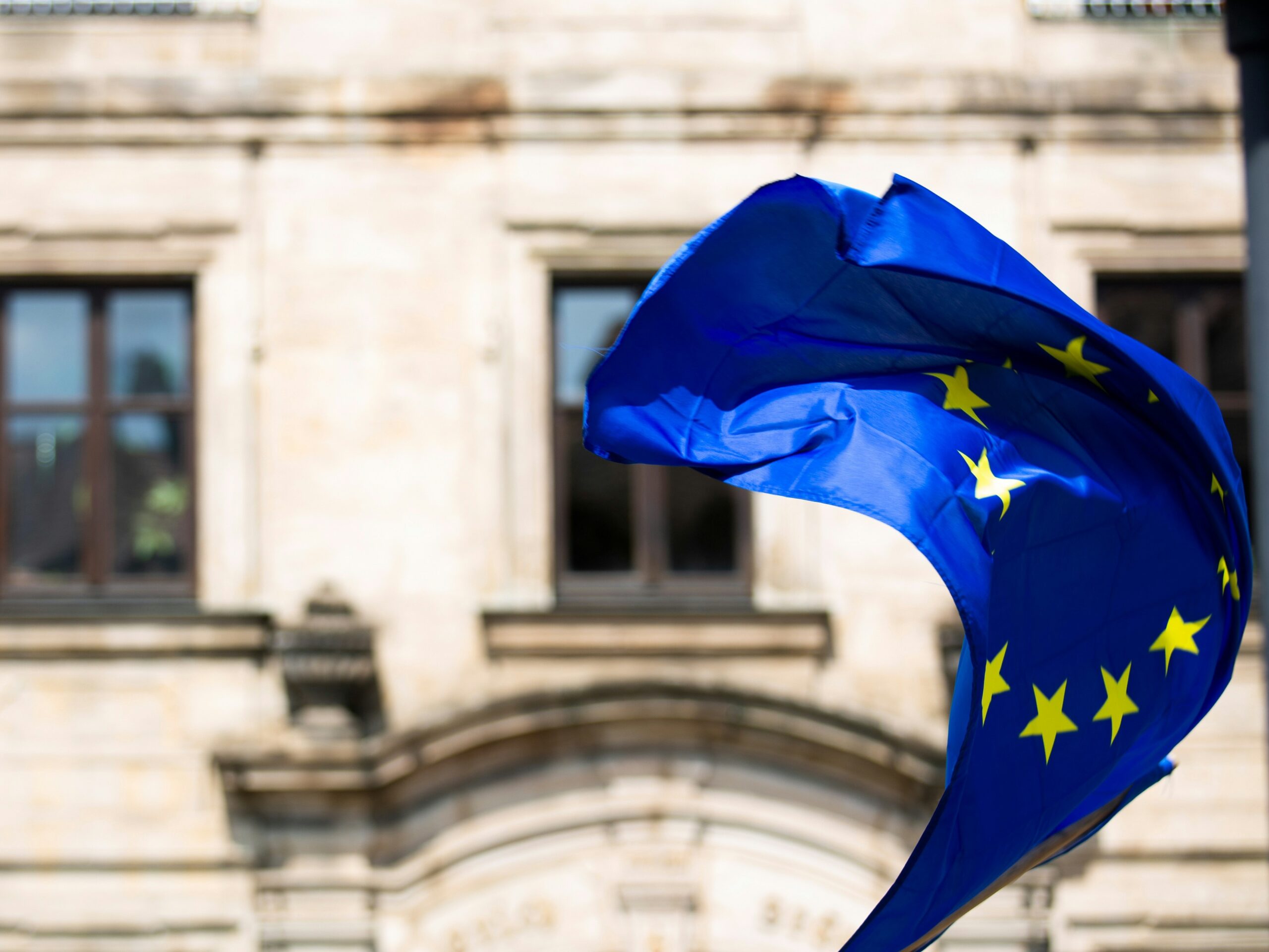 Flaga Unii Europejskiej powiewająca przed budynkiem rządowym