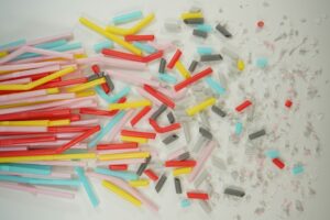 Kolorowe plastikowe rurki i ich fragmenty rozrzucone na jasnym tle