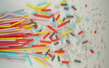 Kolorowe plastikowe rurki i ich fragmenty rozrzucone na jasnym tle