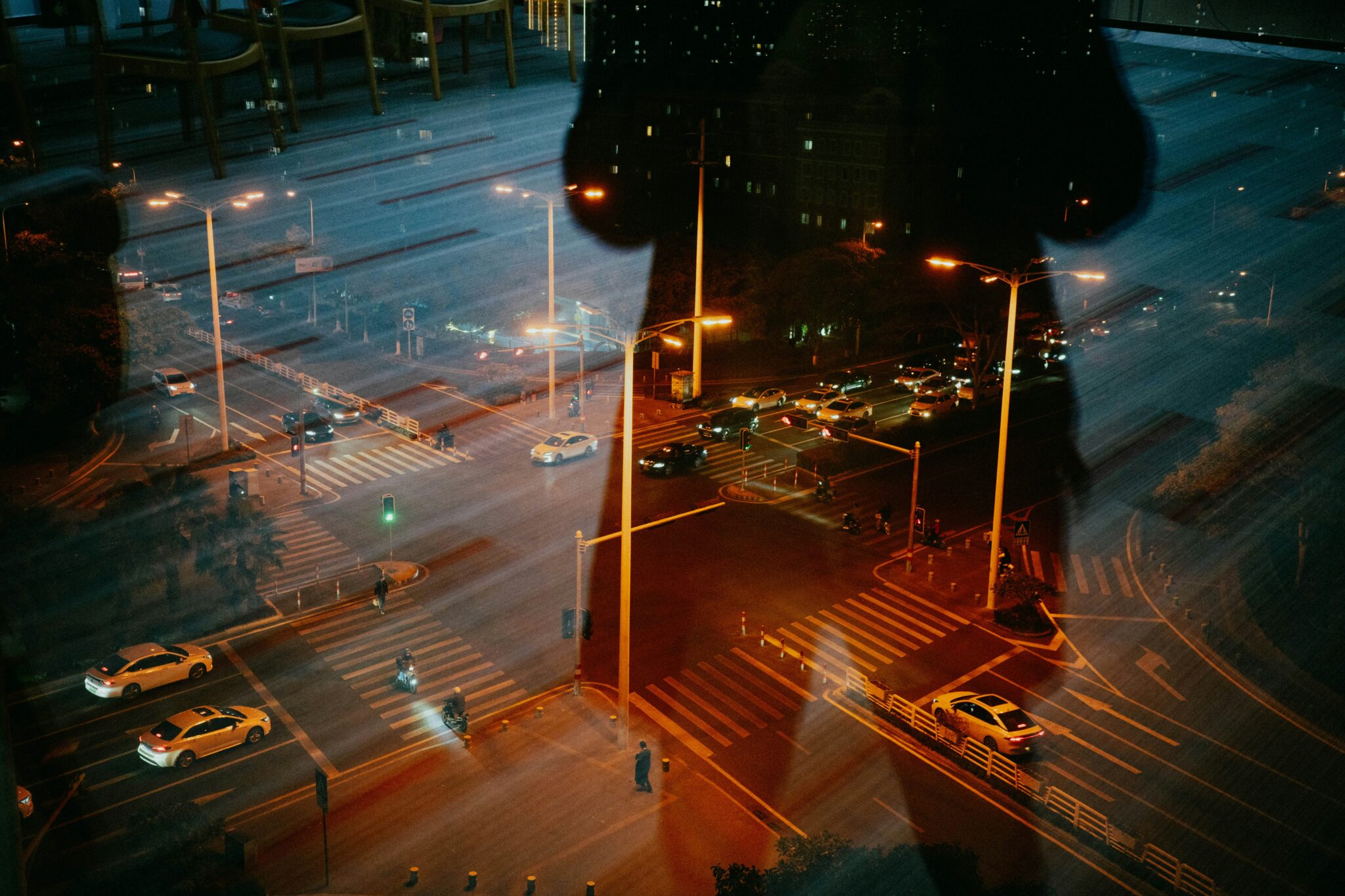 Widok nocnego skrzyżowania z ruchem samochodowym, odbicia i światła uliczne