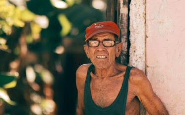 Starszy mężczyzna w upalny dzień stojący przy budynku