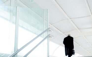 Biznesmen odchodzący samotnie z teczką w biurowym korytarzu