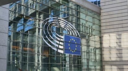 Budynek Parlamentu Europejskiego w Brukseli z flagą Unii Europejskiej.
