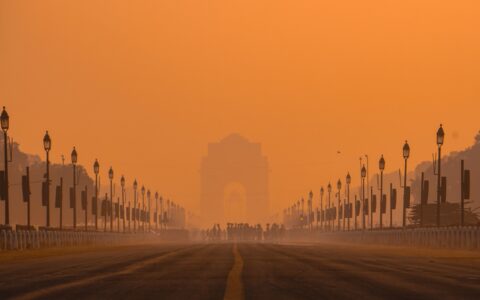 Widok na India Gate w Delhi spowity gęstym smogiem o pomarańczowym odcieniu nieba