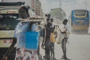 Kobieta sprzedająca jedzenie przy drodze w kraju globalnego Południa w warunkach upału i zanieczyszczenia powietrza