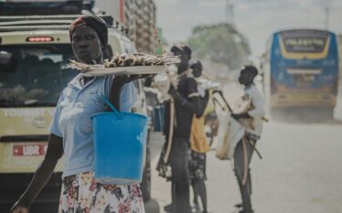 Kobieta sprzedająca jedzenie przy drodze w kraju globalnego Południa w warunkach upału i zanieczyszczenia powietrza
