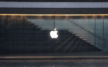 Logo Apple na szklanej fasadzie budynku w deszczu