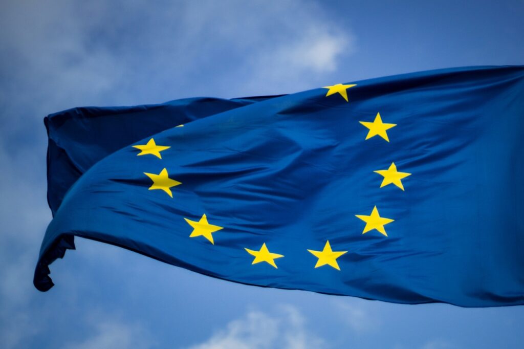 Flaga Unii Europejskiej powiewająca na tle nieba symbolizująca decyzje klimatyczne UE