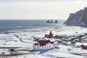 Zimowy krajobraz Islandii z kościołem i widokiem na ocean