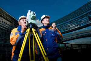 Inżynierowie pracujący z instrumentem pomiarowym na tle nowoczesnej infrastruktury