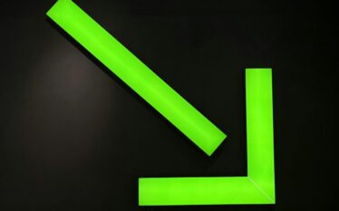 Jaskrawozielona instalacja świetlna w kształcie opadającego wykresu na czarnym tle