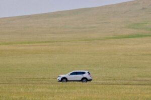Samochód jedzie przez rozległą zielono-żółtą równinę