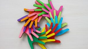 Kolorowe drewniane dłonie symbolizujące różnorodność, równość i inkluzywność w kontekście programów DEI