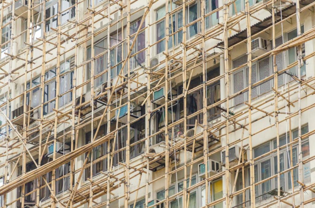 Żółte siatki i bambusowe rusztowania na fasadzie wysokiego budynku w Hongkongu
