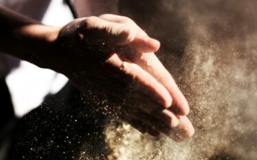 Dłonie otrzepujące drobne cząstki w świetle, symbolizujące zanieczyszczenia mikroplastikiem