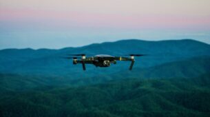 Dron unoszący się nad zalesionym terenem podczas monitoringu środowiskowego