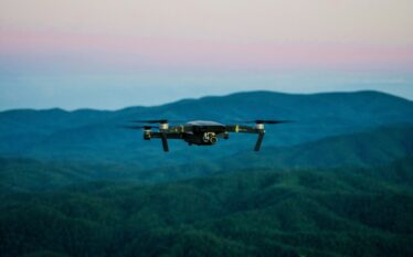 Dron unoszący się nad zalesionym terenem podczas monitoringu środowiskowego