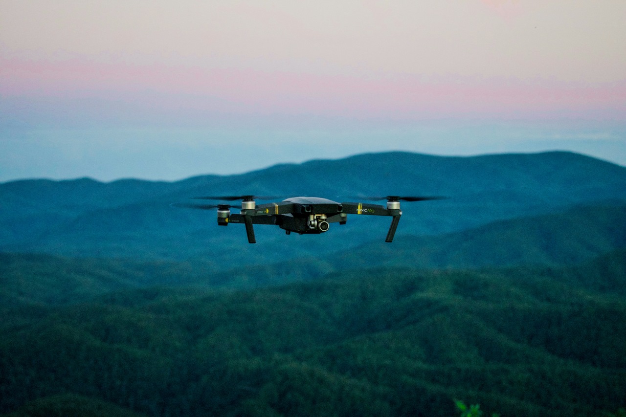 Dron unoszący się nad zalesionym terenem podczas monitoringu środowiskowego
