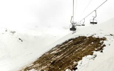 Ośrodek narciarski z niewielką ilością śniegu i odsłoniętą ziemią na stoku