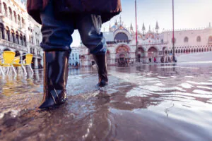 Osoba w kaloszach przechodząca przez zalany plac Świętego Marka w Wenecji
