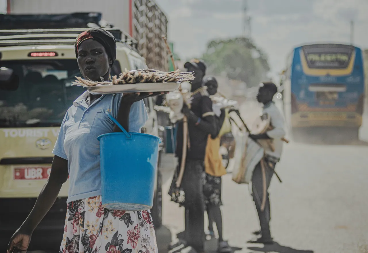 Kobieta sprzedająca jedzenie przy drodze w kraju globalnego Południa w warunkach upału i zanieczyszczenia powietrza