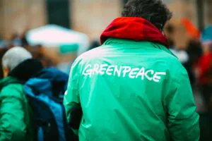 Aktywista w zielonej kurtce z logo Greenpeace podczas demonstracji klimatycznej