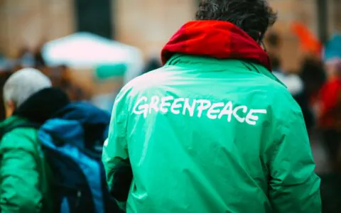 Aktywista w zielonej kurtce z logo Greenpeace podczas demonstracji klimatycznej