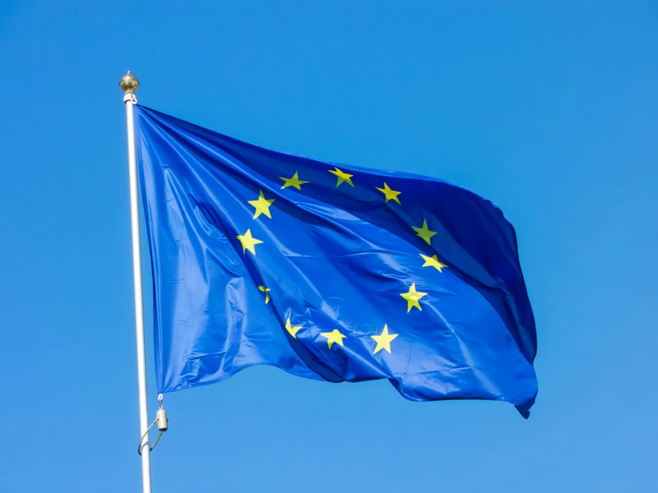 Flaga Unii Europejskiej na tle czystego, błękitnego nieba