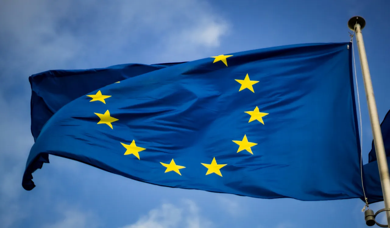 Flaga Unii Europejskiej powiewająca na maszcie przed instytucjami unijnymi