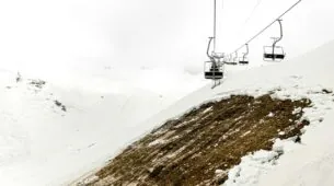 Ośrodek narciarski z niewielką ilością śniegu i odsłoniętą ziemią na stoku